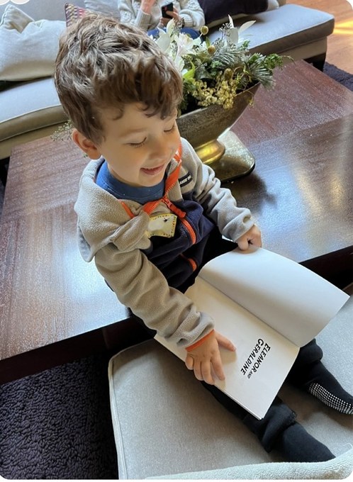 Dr. Rosenbaum's grandson smiling as he turns the pages of Eleanor and Geraldine